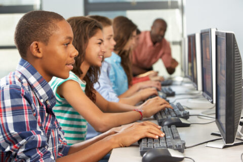 Group Of Students Working At Computers In Classroom