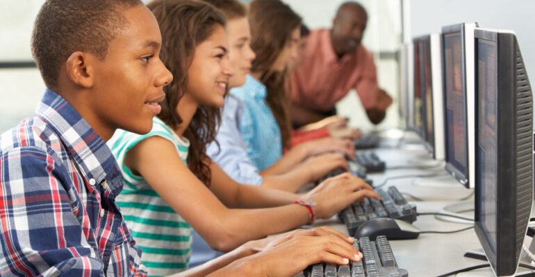 Group Of Students Working At Computers In Classroom