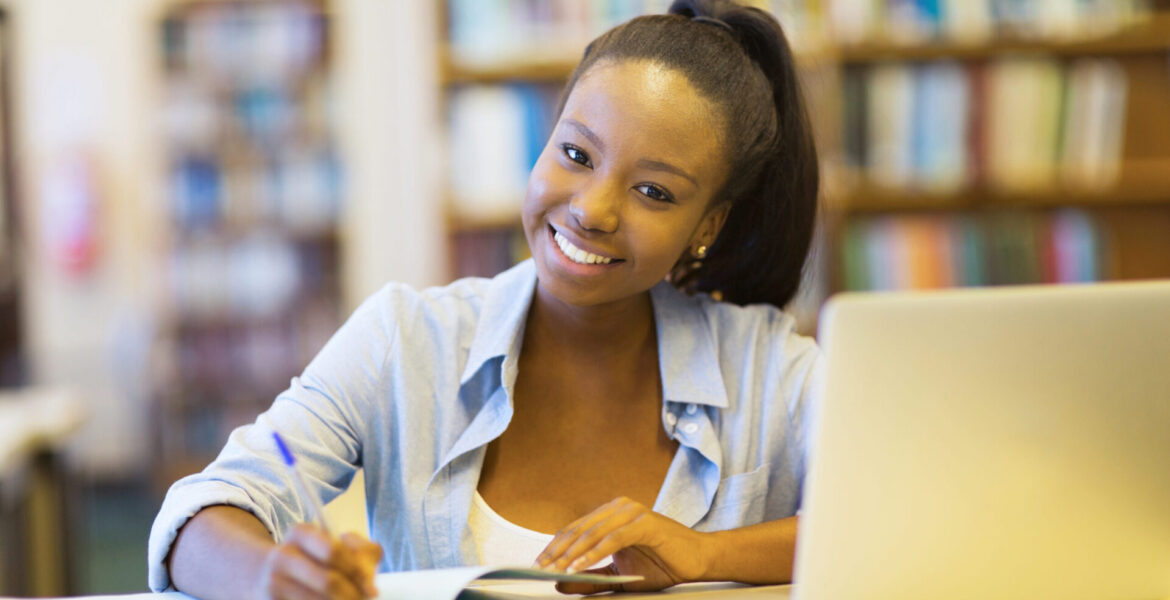 african college student studying a book in library